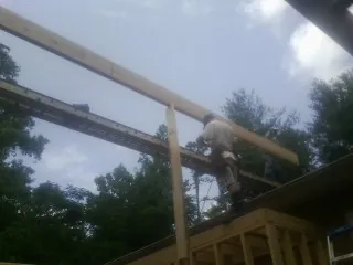 Carpenter setting a ridge beam over a new addition frame — Ice Dam Removal by Roofing Brothers in White