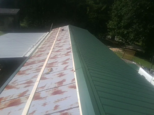 Old rusted panels beside newly installed green metal roofing — Wind Damage Roof Repair by Roofing Brothers in White