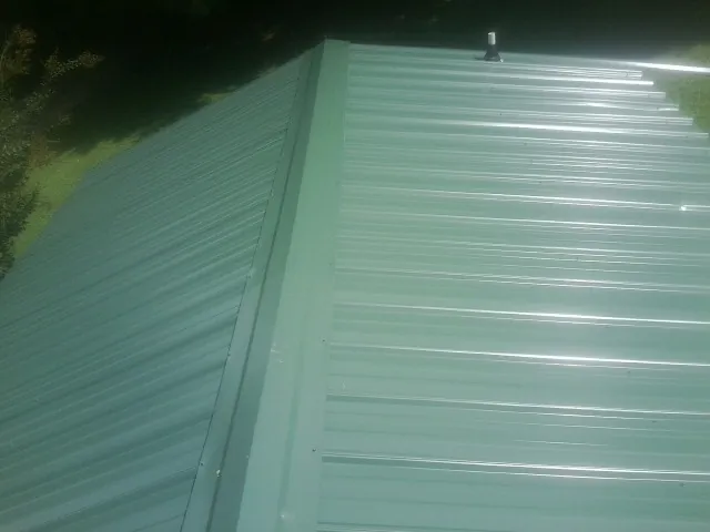 New green metal panels meeting at the ridge of a roof — Flat Roof Repair work by our crew in White